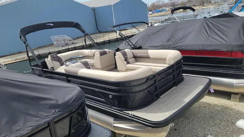 Slide: The Image of 2025 Bennington 23 SL pontoon boat with beige seating, docked at a marina. - 5