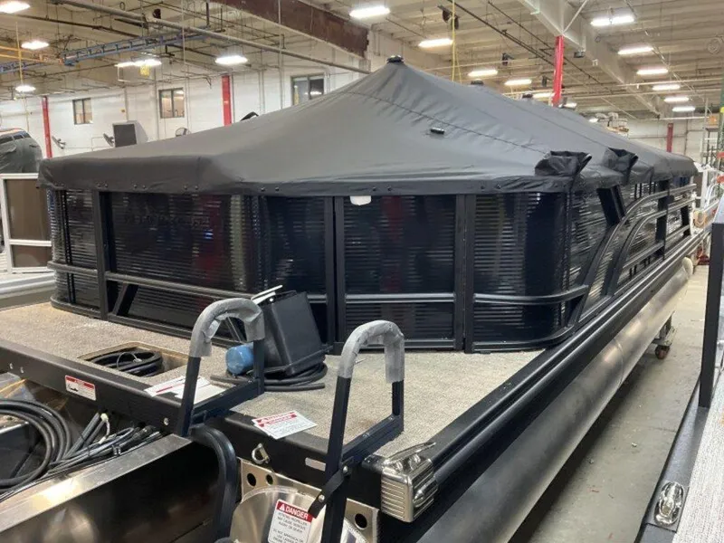 Slide: The Image of 2025 Bennington 23 SL pontoon boat with black cover in a warehouse setting. - 9