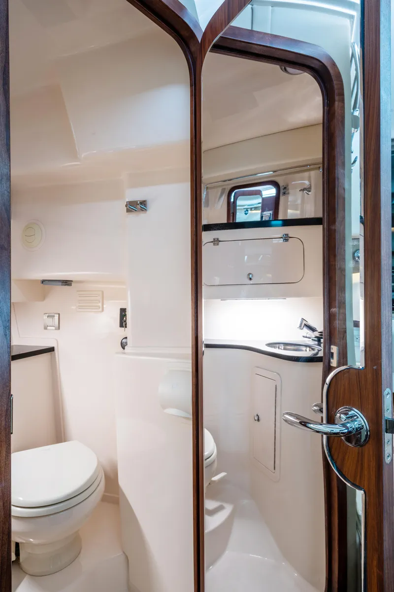 Slide: The Image of 2025 Grady-White 330 Express boat bathroom interior with modern fixtures and wooden accents. - 16