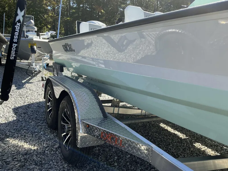 Slide: The Image of 2025 Excel Bay Pro 220 ELITE boat on a trailer, parked on gravel. - 10