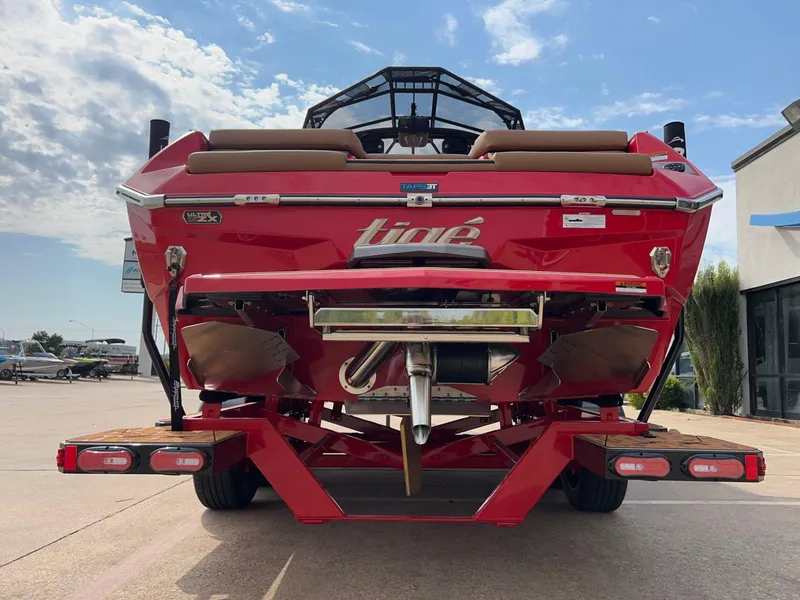Slide: The Image of 2025 Tigé 25ZX Ultre' boat, red exterior, rear view, parked outdoors under a blue sky. - 3