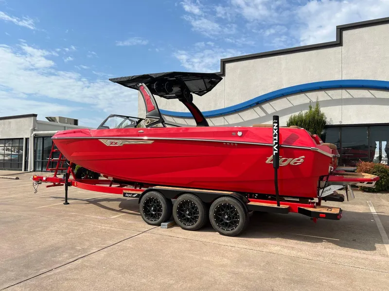 Slide: The Image of 2025 Tigé 25ZX Ultre' boat in vibrant red on a trailer, parked outdoors. - 4