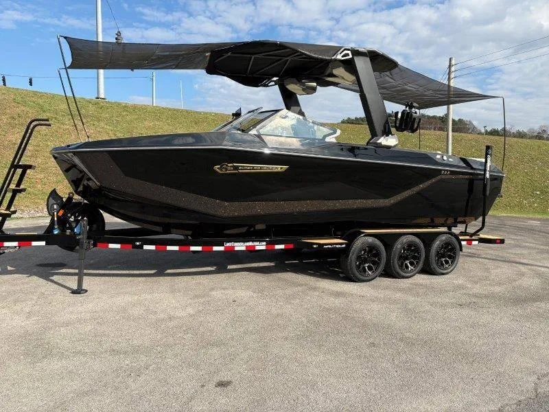 Slide: The Image of 2025 Nautique G25 boat on trailer with canopy, parked outdoors. - 122