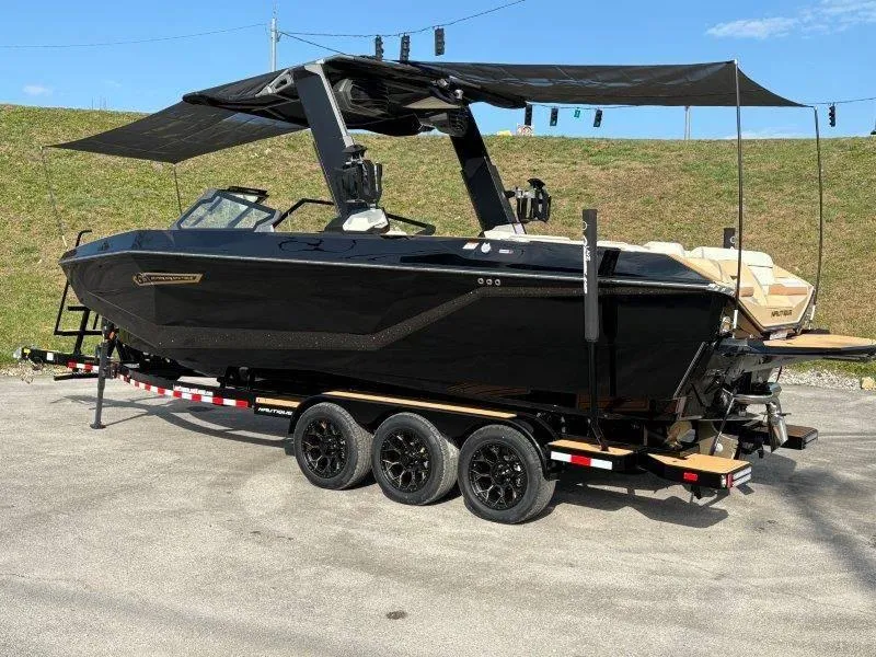 Slide: The Image of 2025 Nautique G25 boat on trailer with black exterior and canopy. - 124
