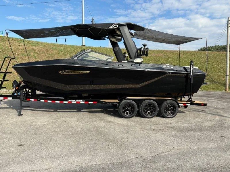 Slide: The Image of 2025 Nautique G25 boat on trailer, sleek black design, parked outdoors. - 126