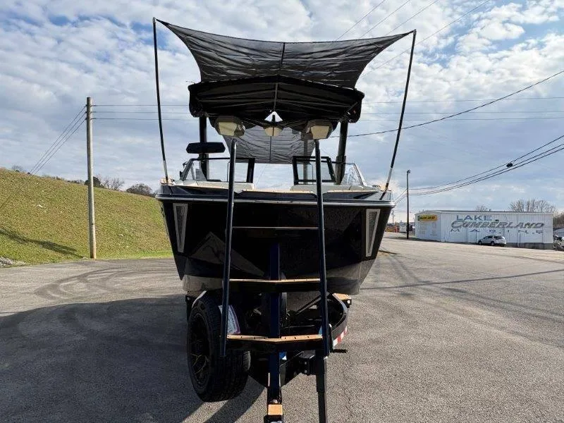 Slide: The Image of 2025 Nautique G25 boat with canopy on trailer, parked outdoors. - 131
