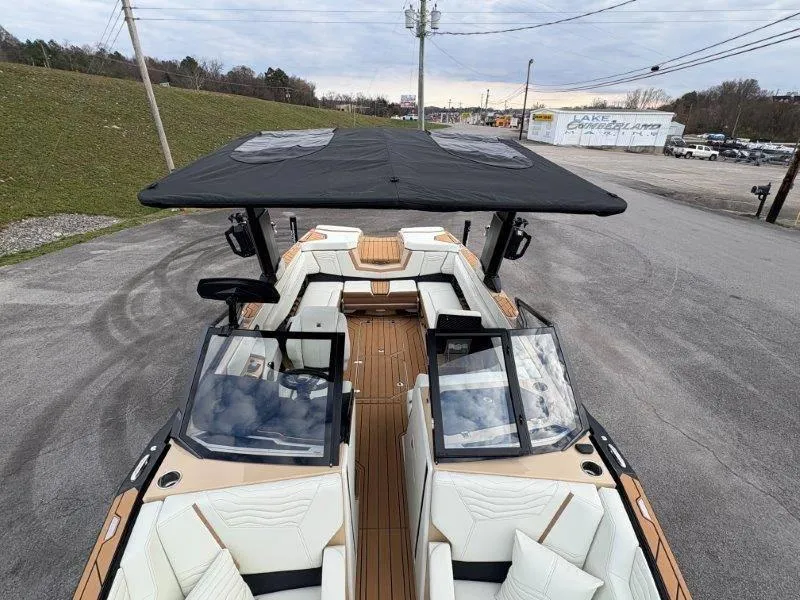 Slide: The Image of 2025 Nautique G25 boat with black canopy and luxurious seating on a paved lot. - 21
