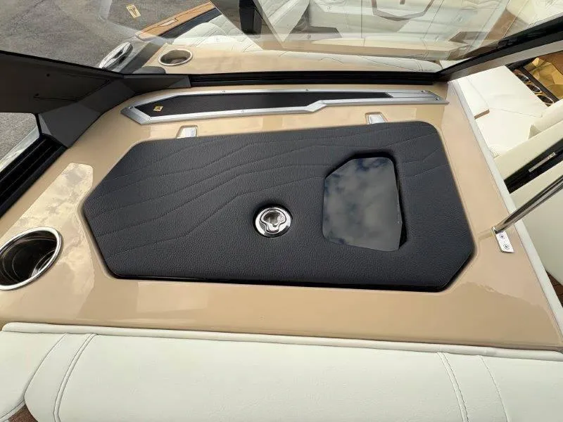 Slide: The Image of 2025 Nautique G25 boat dashboard with sleek black panel and cup holder. - 26