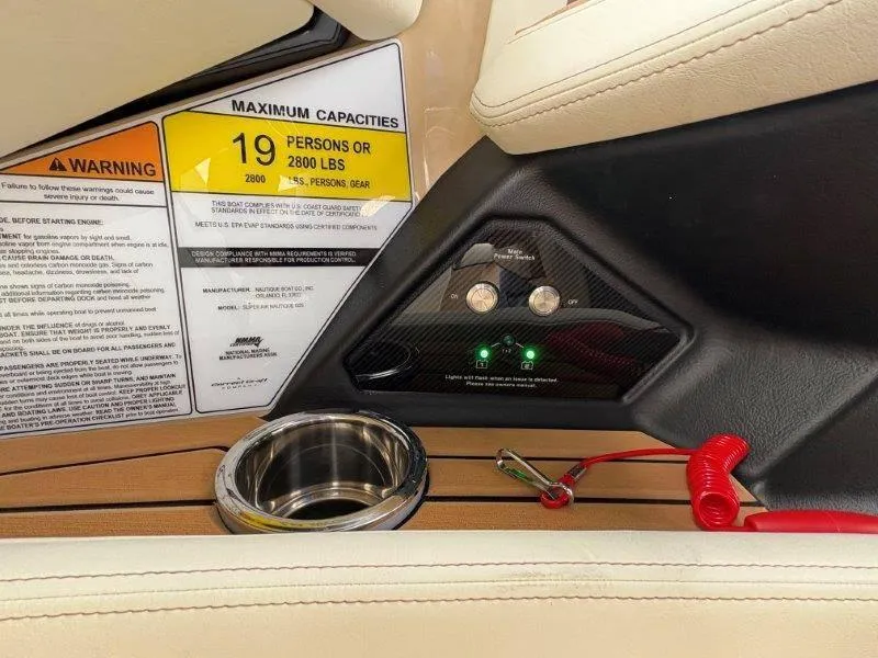 Slide: The Image of 2025 Nautique G25 boat interior, capacity warning label, and control panel. - 44