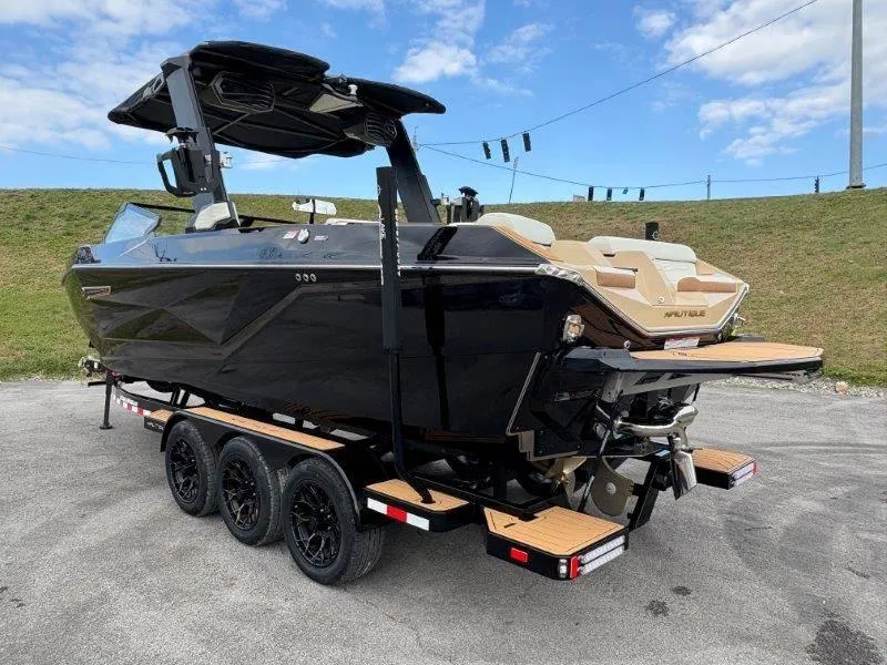 Slide: The Image of 2025 Nautique G25 boat on trailer, sleek black design, parked outdoors. - 5
