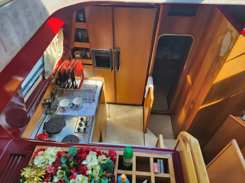 Slide: The Image of Interior of 1987 Posillipo Technema 52 yacht, featuring a compact kitchen with stove and floral decor. - 45