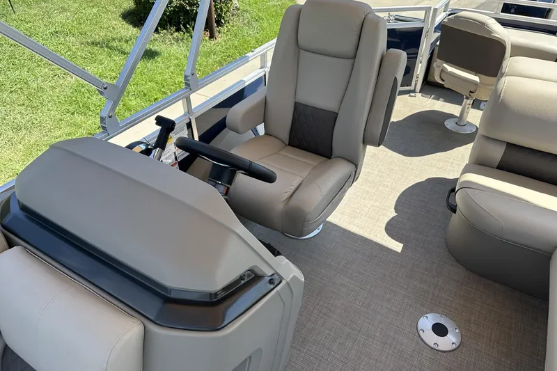 Slide: The Image of 2025 Sun Tracker Fishin' Barge 22 DLX interior with comfortable seating and steering console. - 17