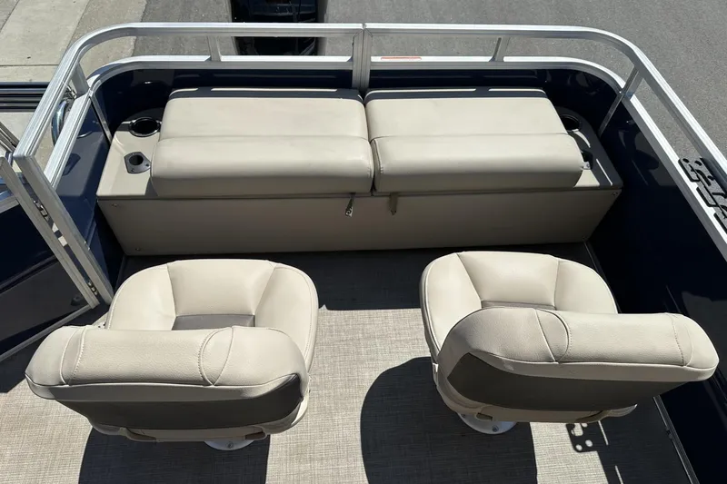 Slide: The Image of 2025 Sun Tracker Fishin' Barge 22 DLX interior with beige seating and cup holders. - 21
