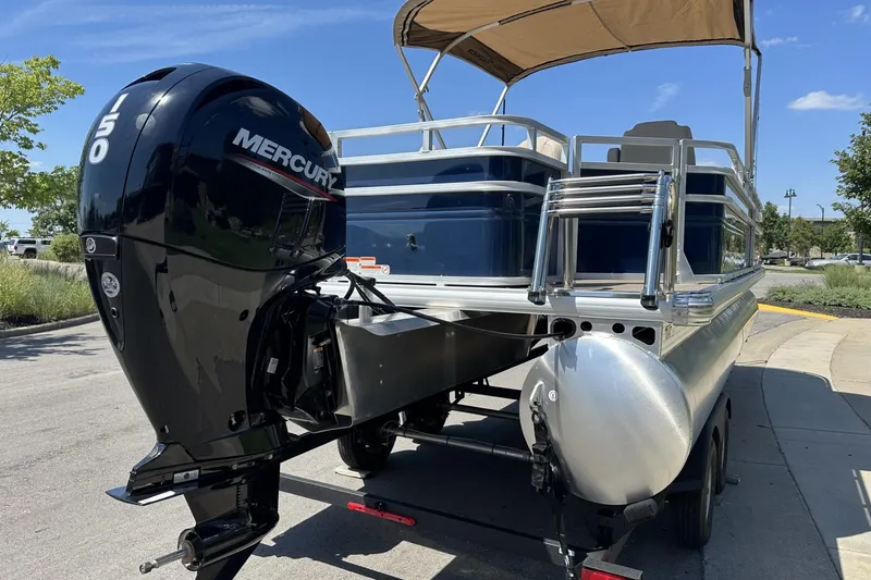 Slide: The Image of 2025 Sun Tracker Fishin' Barge 22 DLX with Mercury 150 engine, parked outdoors. - 4