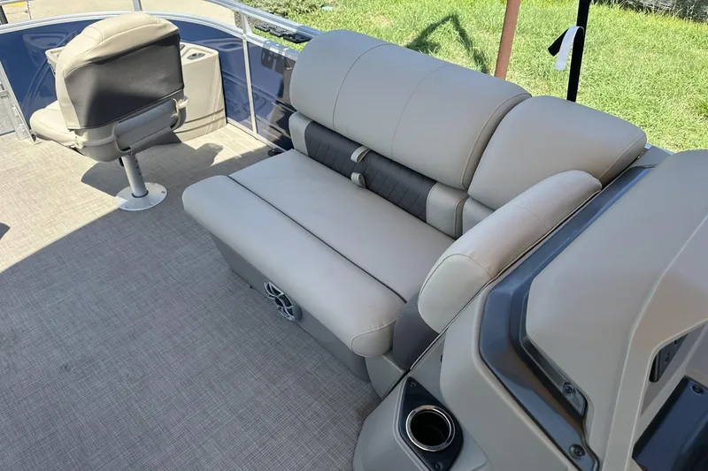 Slide: The Image of 2025 Sun Tracker Fishin' Barge 22 DLX interior with beige seating and carpeted floor. - 16
