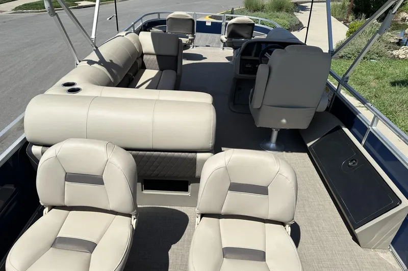Slide: The Image of 2025 Sun Tracker Fishin' Barge 22 DLX interior with beige seating and steering console. - 23