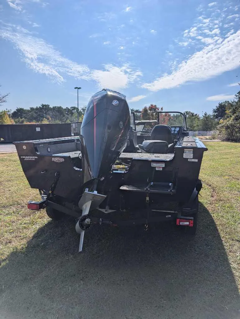 Slide: The Image of 2025 Tracker Targa V-19 WT boat, rear view, parked on grass under a clear sky. - 2
