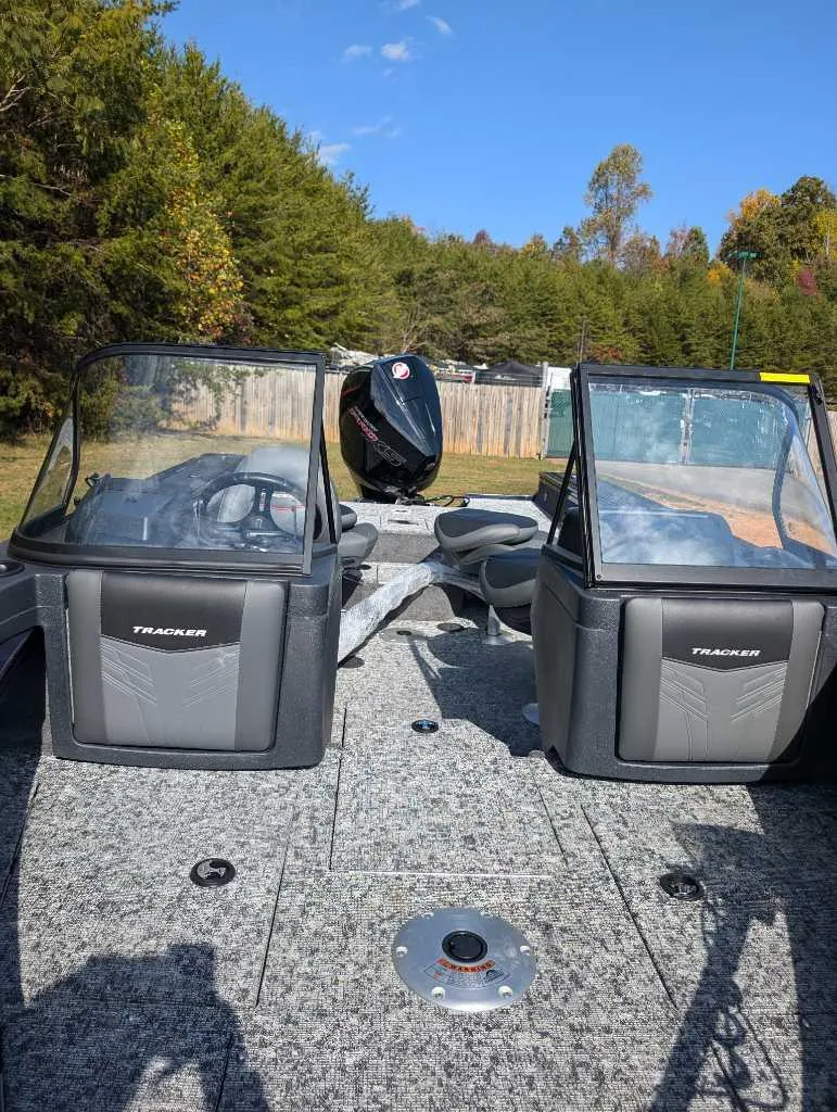 Slide: The Image of 2025 Tracker Targa V-19 WT boat interior with dual consoles, forest backdrop. - 3