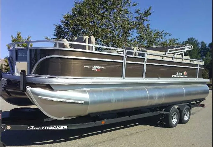 The Image of 2025 Sun Tracker Sportfish 24 XP3 pontoon boat on trailer, parked outdoors. - 0