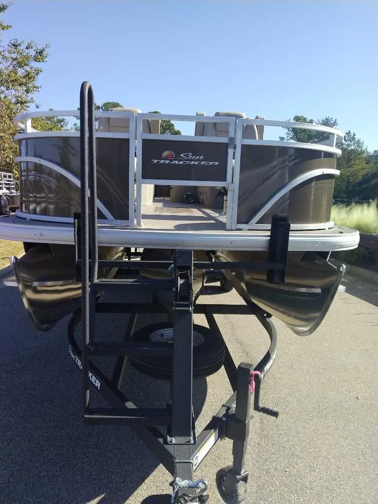 Slide: The Image of 2025 Sun Tracker Sportfish 24 XP3 pontoon boat on trailer, parked outdoors. - 3