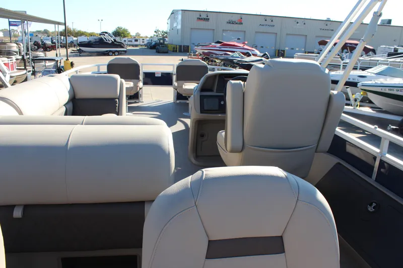 Slide: The Image of 2025 Sun Tracker Fishin' Barge 22 DLX interior with beige seating and helm. - 22