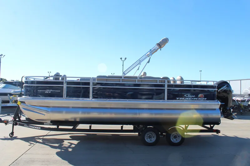 Slide: The Image of 2025 Sun Tracker Fishin' Barge 22 DLX pontoon boat on trailer, sunny day. - 3