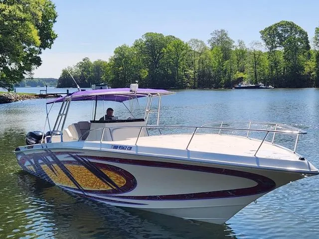 Slide: The Image of 2003 Fountain 38 Center Console boat on a serene lake with lush green trees. - 1