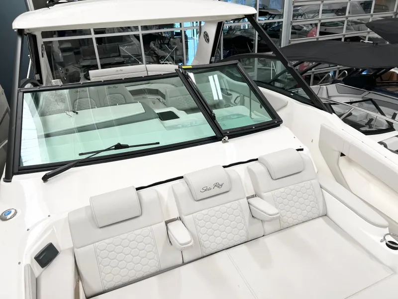 Slide: The Image of 2025 Sea Ray Sundancer 320 boat with white seating and sleek design in showroom. - 11