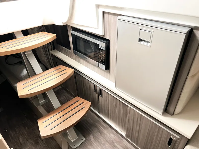 Slide: The Image of Interior of 2025 Sea Ray Sundancer 320 with modern kitchen and wooden steps. - 15