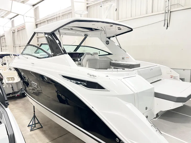 Slide: The Image of 2025 Sea Ray Sundancer 320 yacht in showroom, sleek design, black and white exterior. - 2