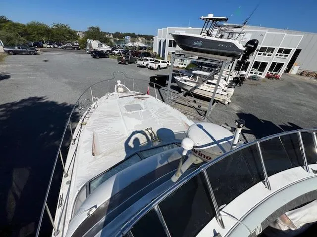 Slide: The Image of 1985 Trojan 11 Meter Express boat in a marina, surrounded by other vessels and vehicles. - 22
