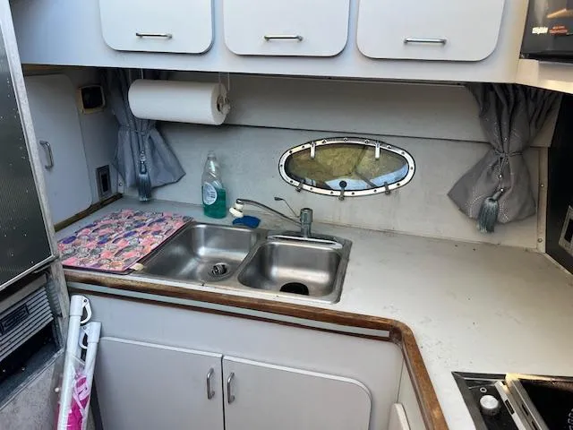 Slide: The Image of 1985 Trojan 11 Meter Express boat kitchen with sink, cabinets, and porthole window. - 6