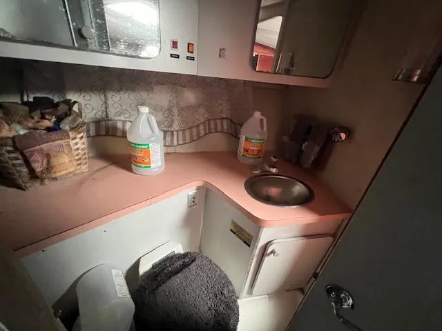 Slide: The Image of 1985 Trojan 11 Meter Express boat bathroom with sink, counter, and cleaning supplies. - 9