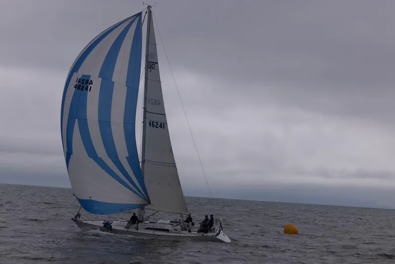 Slide: The Image of 1985 C&C 41 sailboat with blue and white sail on the sea. - 2