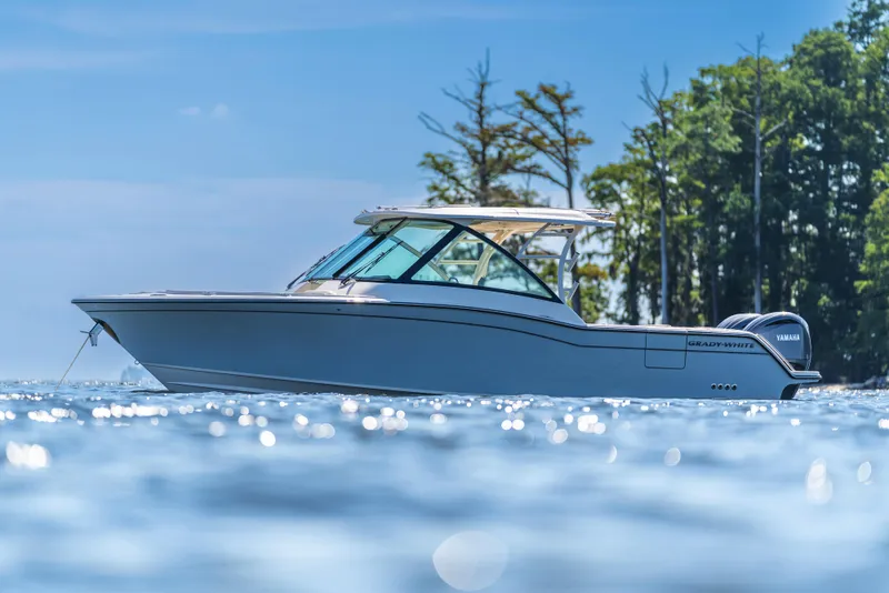 The Image of 2025 Grady-White Freedom 325 boat on water, sunny day, trees in background. - 0