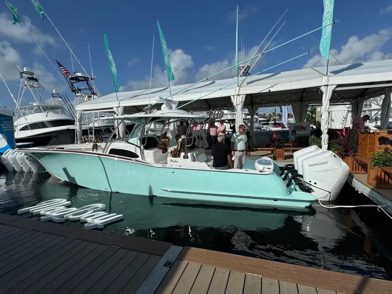 Slide: The Image of 2025 Mag Bay 38 Center Console boat docked at marina, turquoise hull, people onboard. - 27