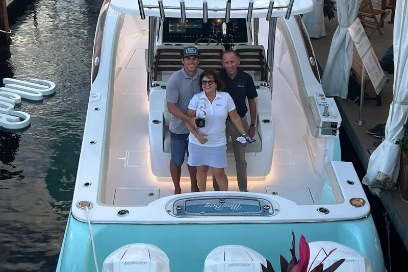 Slide: The Image of 2025 Mag Bay 38 Center Console boat with three people on deck at a marina. - 29