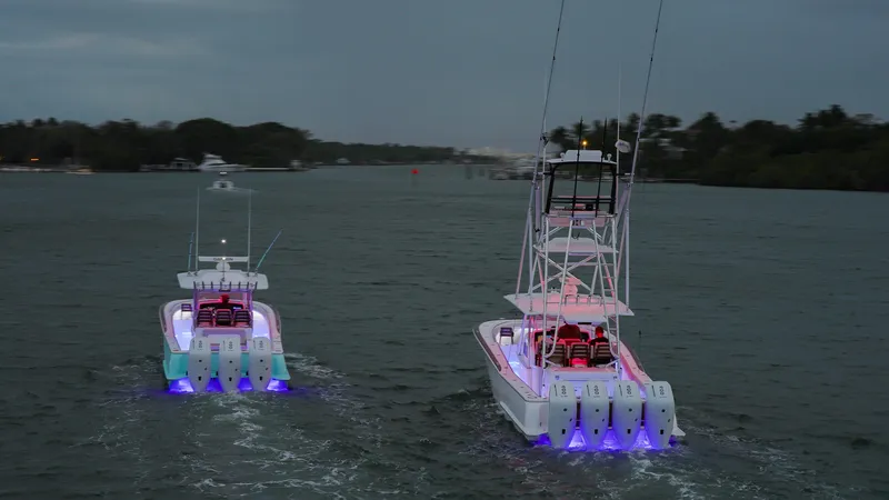 Slide: The Image of 2025 Mag Bay 38 Center Console boats with illuminated engines on the water at dusk. - 18