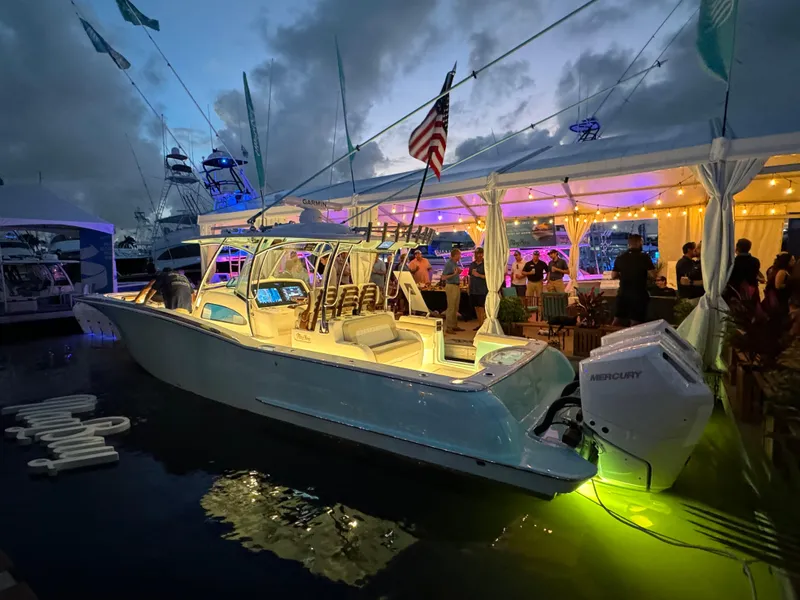 Slide: The Image of 2025 Mag Bay 38 Center Console boat illuminated at a lively dockside event. - 22
