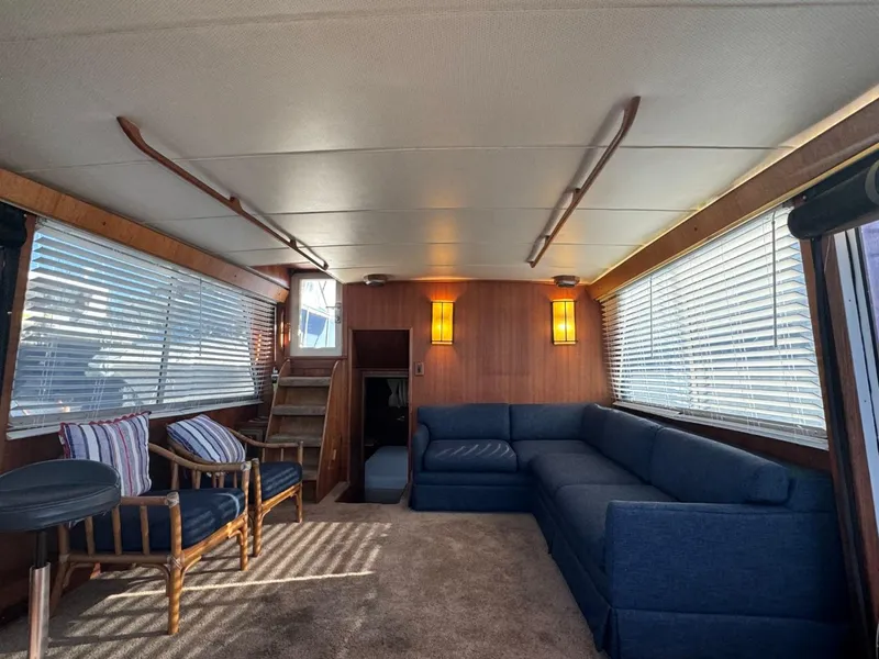 Slide: The Image of 1984 Tollycraft 48 Cockpit Motor Yacht interior with blue sofa, wooden accents, and natural light. - 22