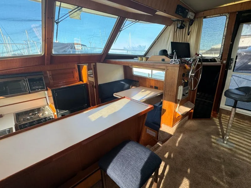 Slide: The Image of 1984 Tollycraft 48 Cockpit Motor Yacht interior with helm, seating, and kitchen area. - 25
