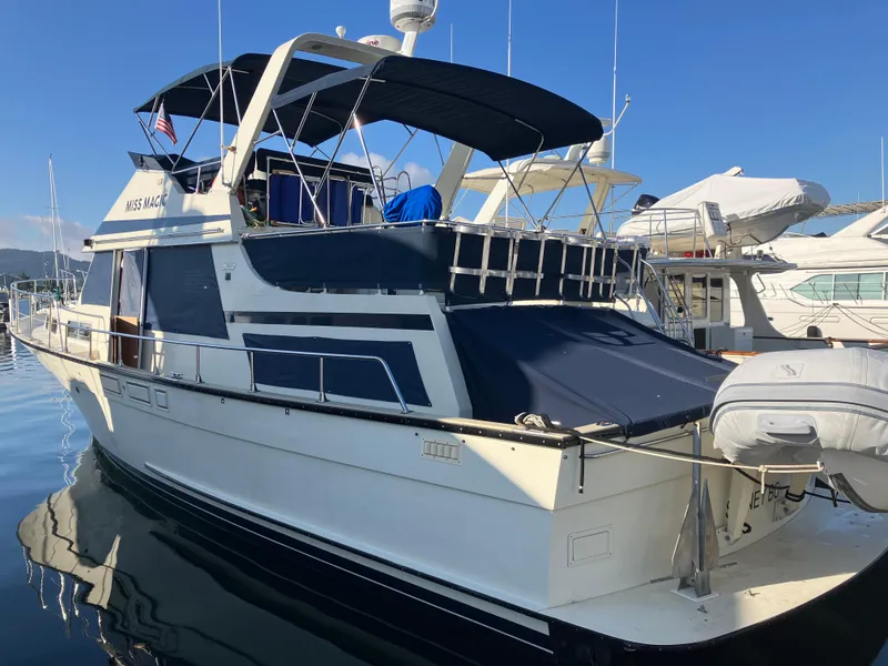 Slide: The Image of 1984 Tollycraft 48 Cockpit Motor Yacht docked in marina, featuring blue canopy and sleek design. - 3