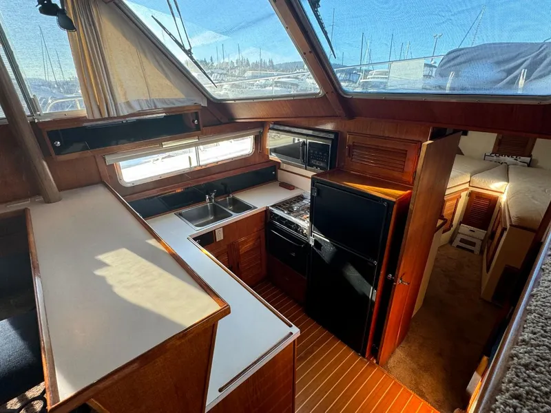 Slide: The Image of 1984 Tollycraft 48 Cockpit Motor Yacht interior with kitchen, wood finishes, and natural light. - 36