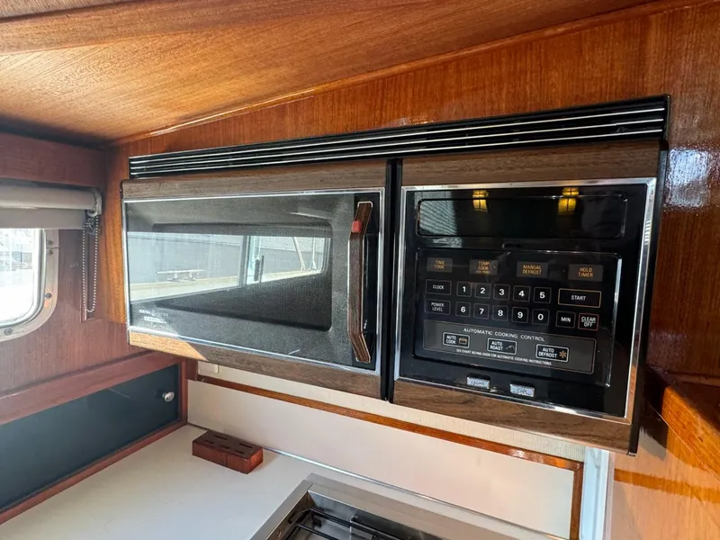 Slide: The Image of 1984 Tollycraft 48 Cockpit Motor Yacht kitchen with built-in microwave and wood paneling. - 40