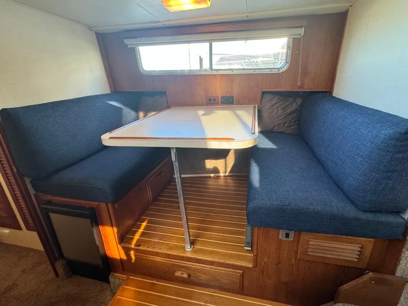 Slide: The Image of 1984 Tollycraft 48 Cockpit Motor Yacht interior with blue cushioned seating and wooden table. - 44