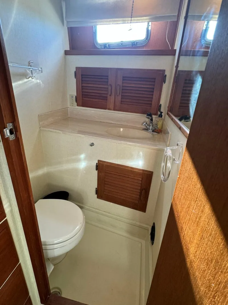 Slide: The Image of 1984 Tollycraft 48 Cockpit Motor Yacht bathroom with wooden cabinets and compact design. - 48