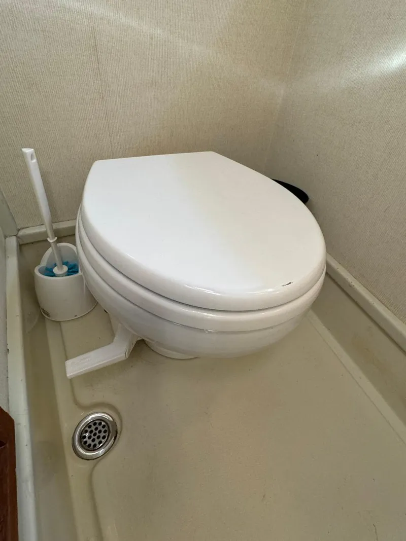 Slide: The Image of 1984 Tollycraft 48 Cockpit Motor Yacht bathroom with toilet and cleaning brush. - 49