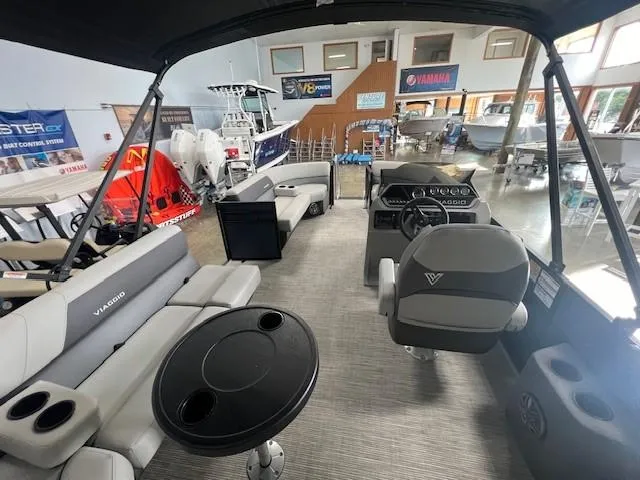 Slide: The Image of 2025 Viaggio Lago V 18 pontoon boat interior in showroom with seating and helm. - 11