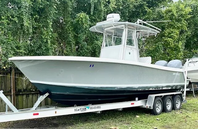 Slide: The Image of 2011 Contender 28 Sport boat on trailer, parked outdoors near trees. - 1