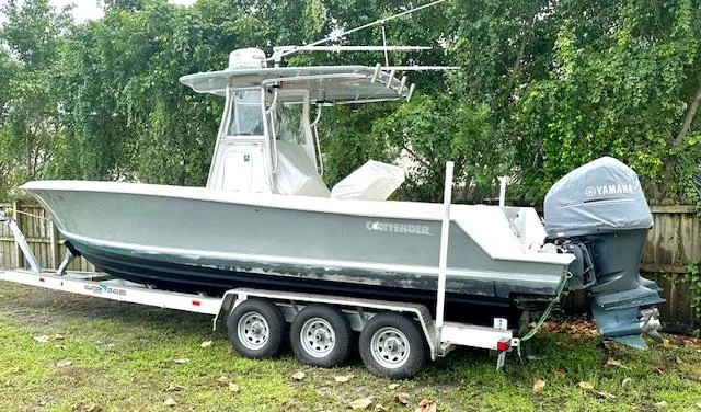 Slide: The Image of 2011 Contender 28 Sport boat on trailer with Yamaha outboard, parked outdoors. - 2